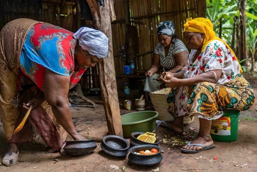 Women engaged in food preparation outdoors, with cooking utensils and a green bucket visible. 2