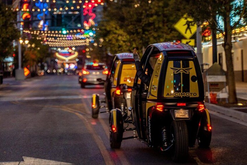 Una calle iluminada con luces brillantes de noche, con una motocicleta y un automóvil. 5