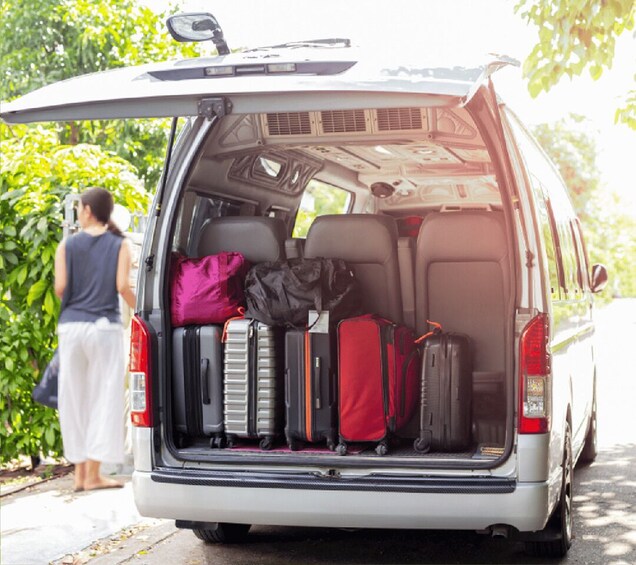 A white van with its back door open, luggage loaded inside, and a person standing beside it. 3