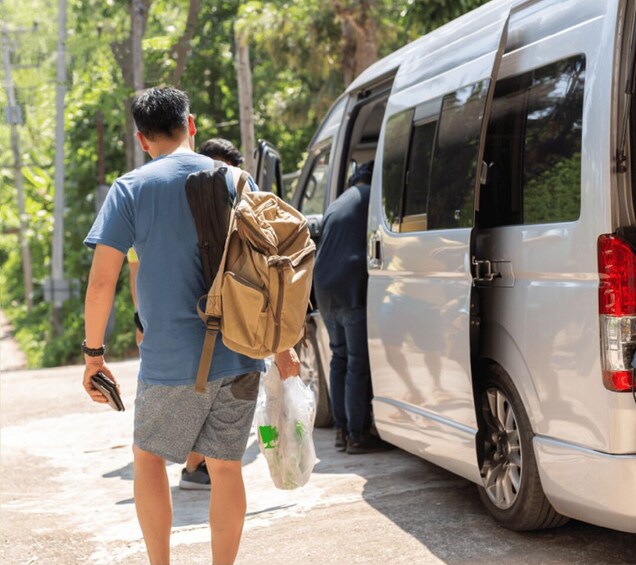 A person walking away from a parked van, carrying a backpack and a plastic bag. 4