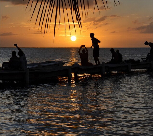 A sunset over water with people on a dock. 1
