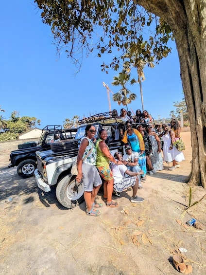 A group of people standing around a black vehicle with a raised platform, under a clear blue sky. 1