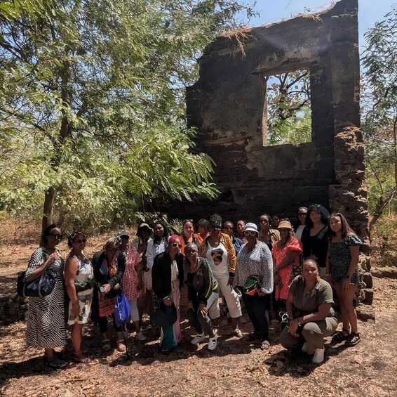 A group of people posing in front of an ancient stone structure with a rectangular window. 2