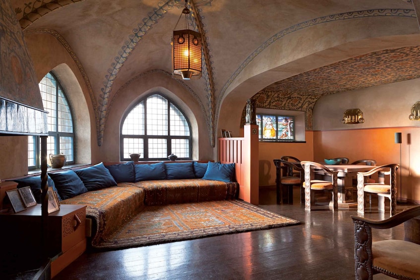 A room with a large arched window, a wooden bench, and a table with chairs. 2