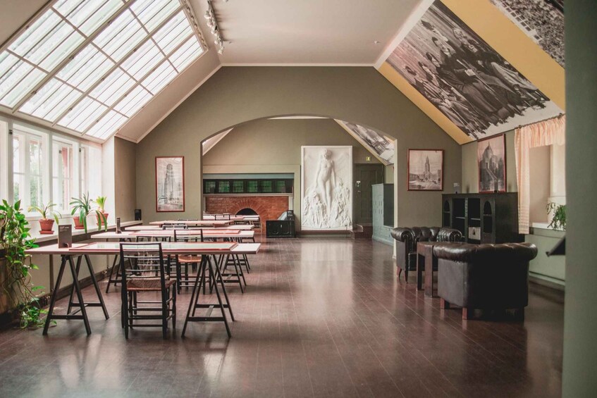 A spacious room with a high ceiling, large windows, a fireplace, and a seating area with leather sofas. 5