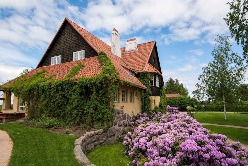 A house with a red-tiled roof, ivy-covered walls, and a purple flower garden. 1