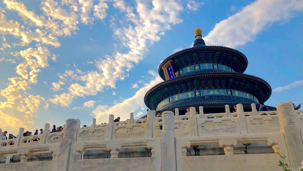 A multi-tiered temple with intricate blue and gold decorations, set against a backdrop of a partly cloudy sky. 1