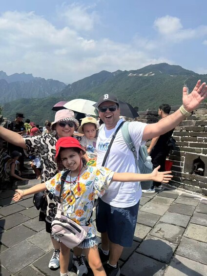 A group of people at a historical site with stone walls and a mountainous backdrop. 4