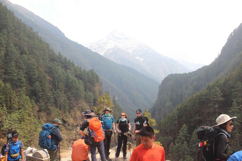 A group of hikers on a mountain trail with a snow-capped peak in the background. 2