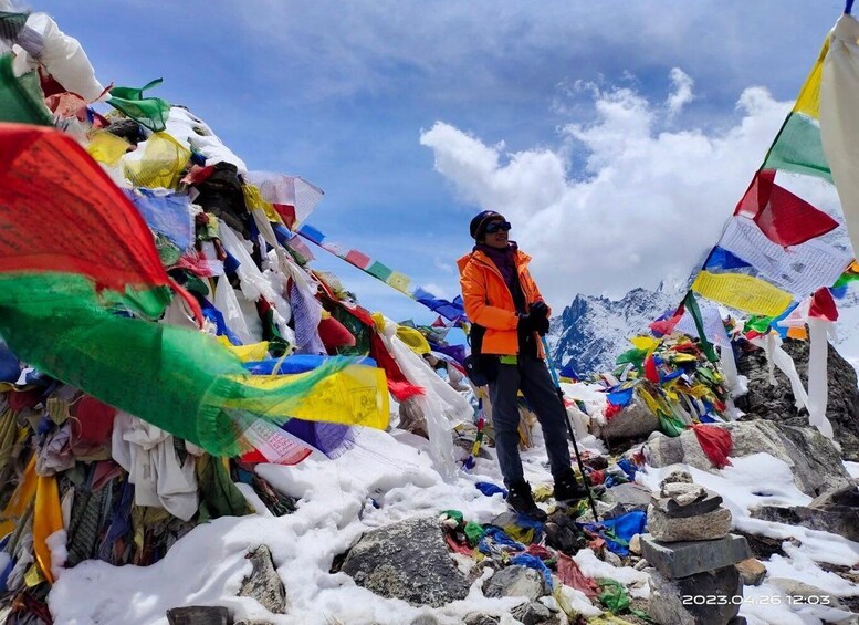 A person standing on a snowy mountain peak with colorful prayer flags. 1