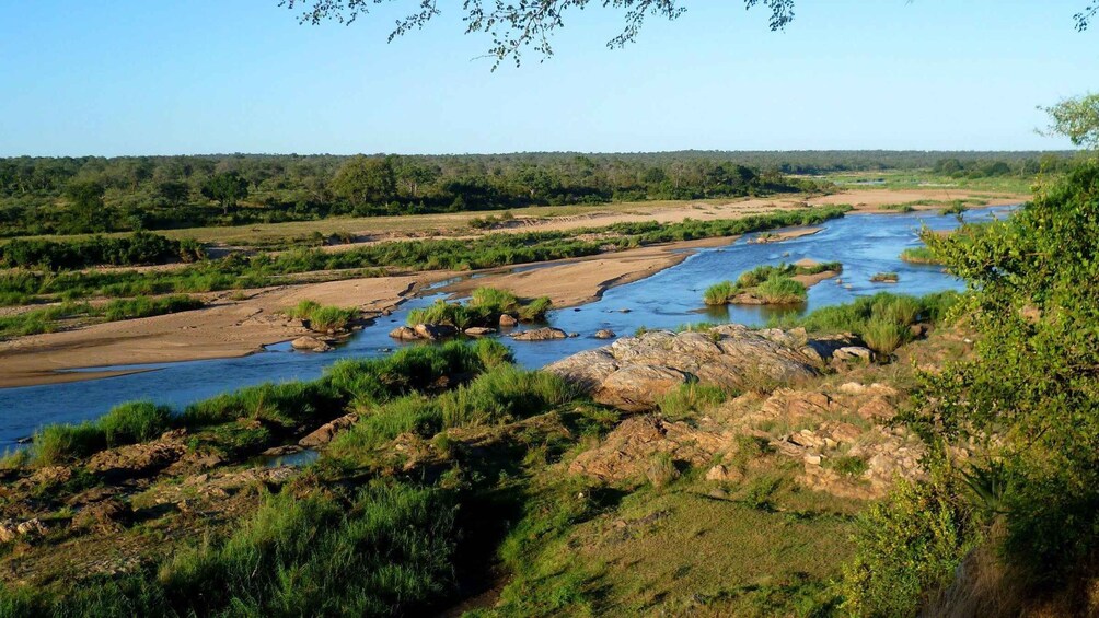 A river meandering through a landscape with dense greenery and rocky terrain. 2