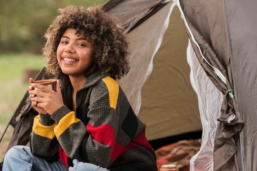A person sitting in front of a tent. 1