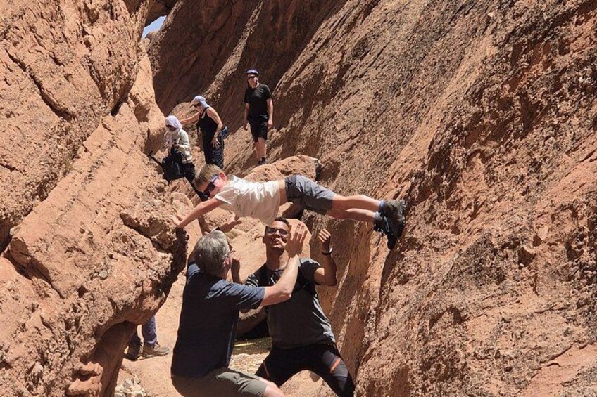 A group of people climbing a steep, rocky canyon wall. 1