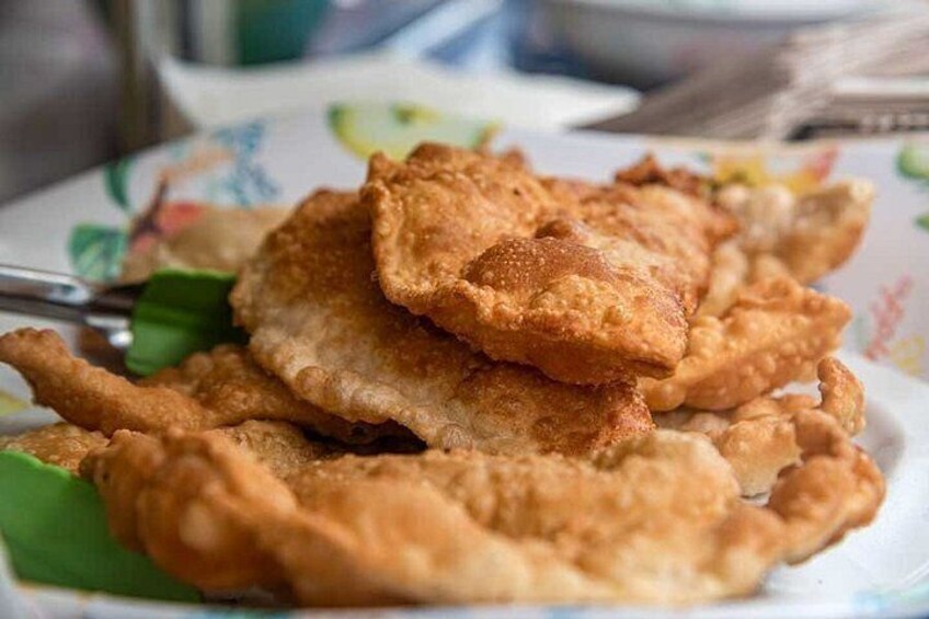 A plate of fried food, possibly fritters, with a green leaf garnish. 5