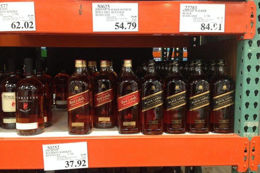 Planken vol met verschillende flessen whisky, elk voorzien van merknaam en prijs. 2