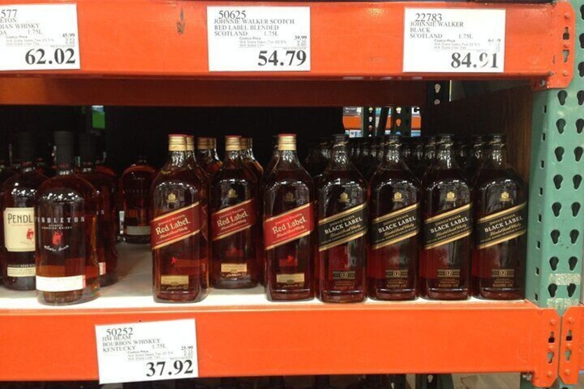 A shelf with various whiskey bottles, including brands like Johnnie Walker and Black Label, with price tags above them. 3