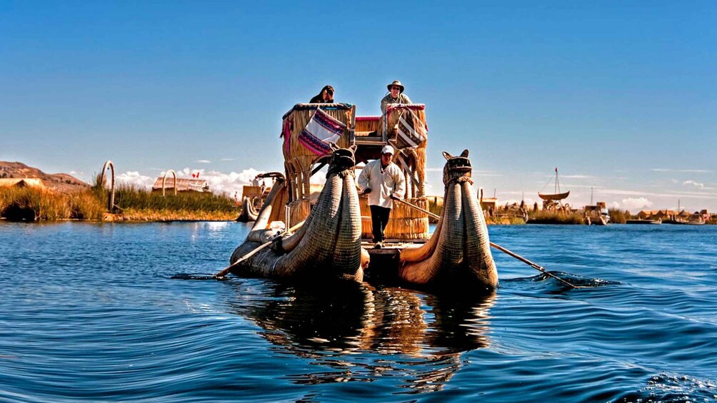 A traditional boat with a thatched roof and two people on it, floating on water. 3