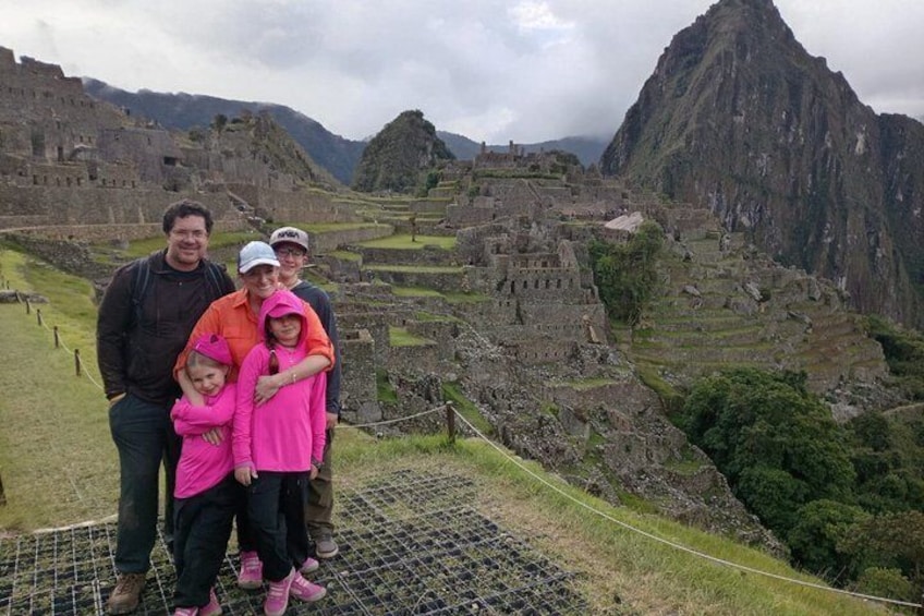 Una familia posando frente a las ruinas de Machu Picchu, con montañas al fondo. 3