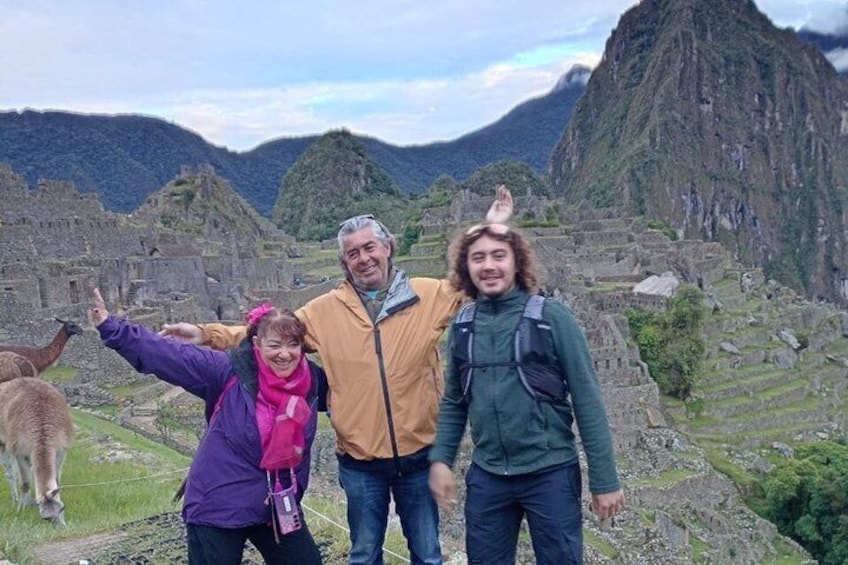 Un grupo de personas frente a las ruinas de Machu Picchu, con llamas al fondo. 2