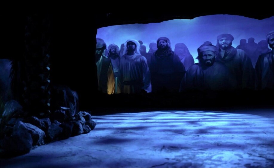 A group of people in historical attire in a dimly lit setting with a blue hue. 3