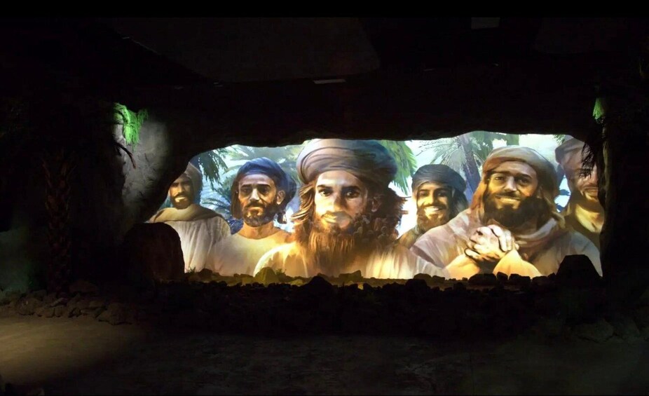 A cave with a mural of people. 2