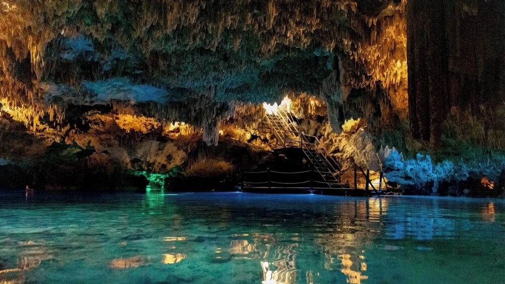 A cave with stalactites, a boat, and a person in the water. 3