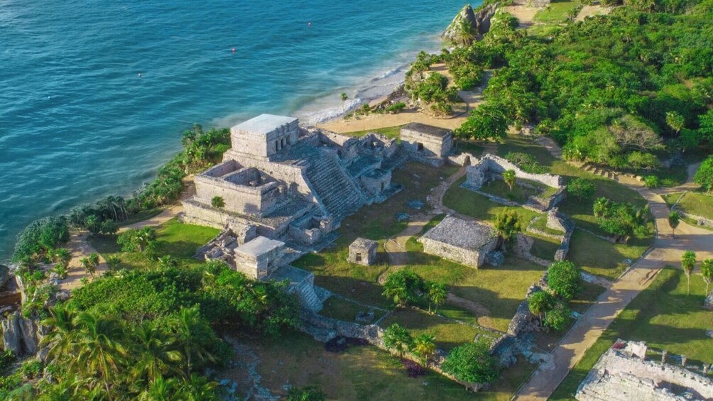An ancient Mayan city with stone structures and a beach. 2