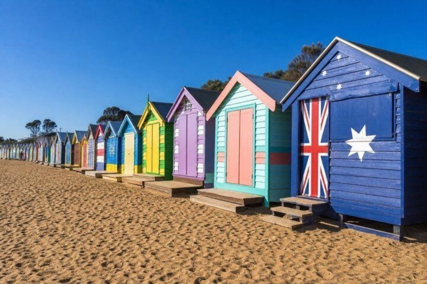 A row of colorful beach huts with steps leading up to them. 1