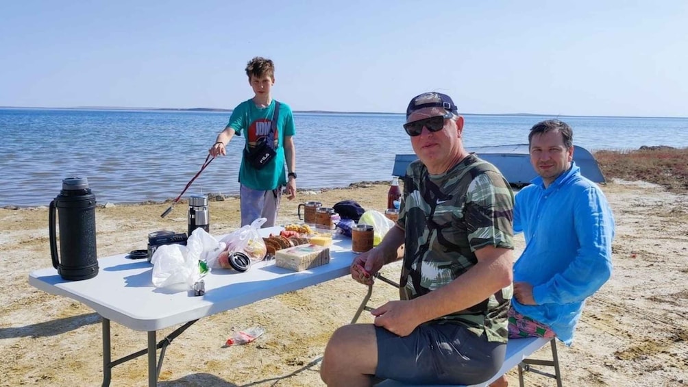 A picnic setup on a sandy beach with a table, food, and a water bottle. 5