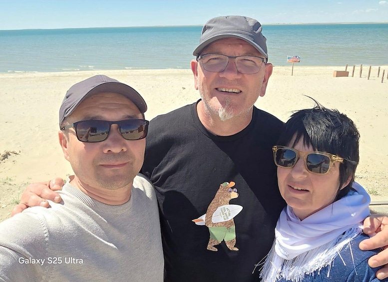 Three people on a beach with a clear sky and calm sea. 3