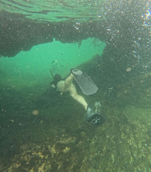 A diver underwater with fins, surrounded by bubbles and a greenish underwater environment. 2