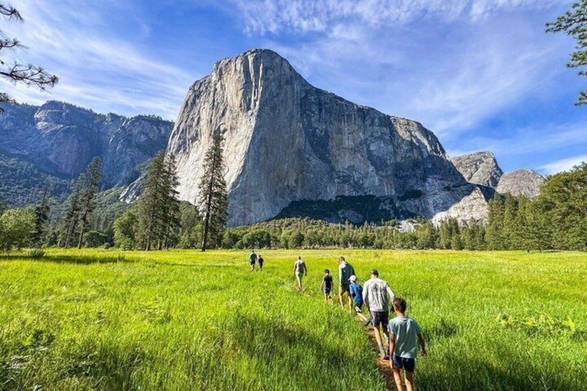 Un groupe de personnes fait de la randonnée sur un sentier, avec une grande montagne en arrière-plan. 1