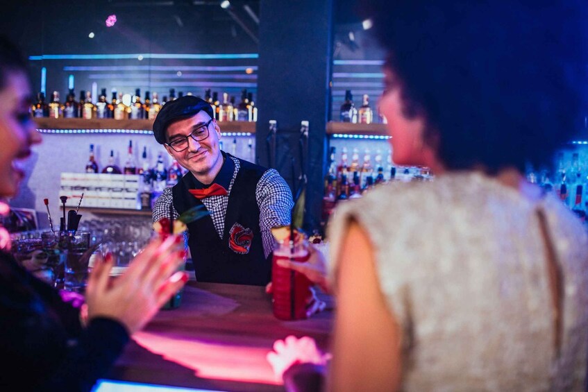 A bartender at a bar with a well-stocked shelf of bottles in the background. 5
