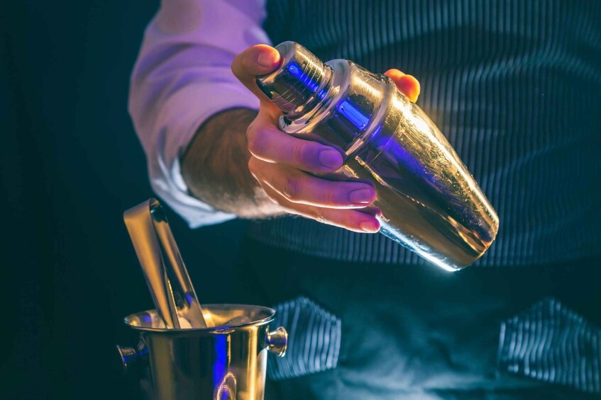 A person holding a golden cocktail shaker. 3