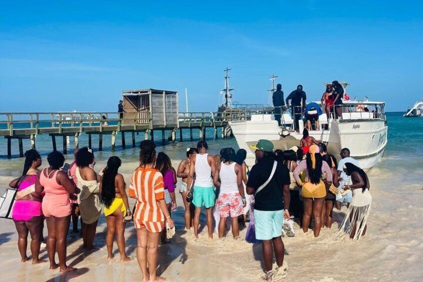 A group of people on a beach near a dock with a boat. 5
