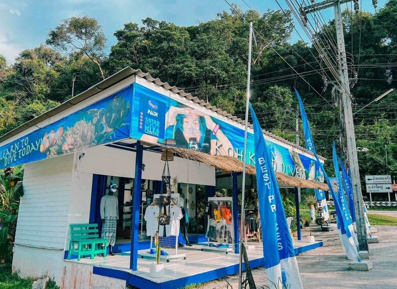 A small building with a blue and white facade, a sign reading 'PADI STAR DIVE CENTRE,' and a thatched roof. 3