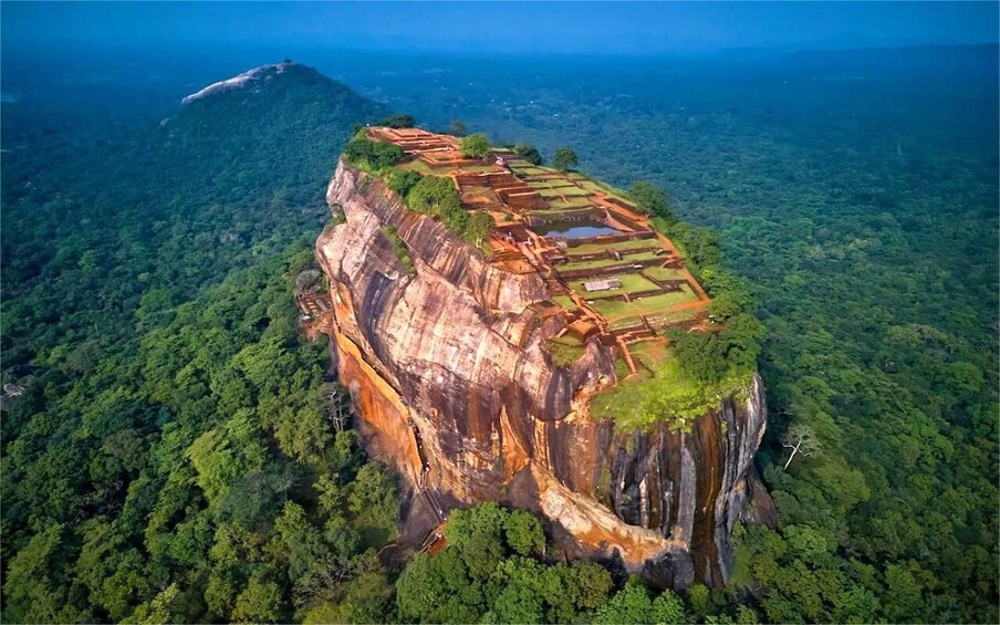 A cliffside with terraced structures and dense forest. 1