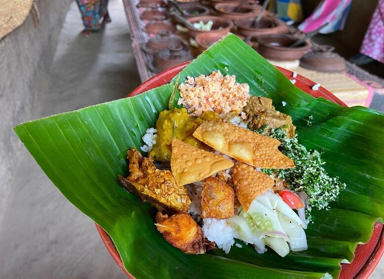 A traditional dish served on a banana leaf with rice, fried items, and a side of vegetables. 4