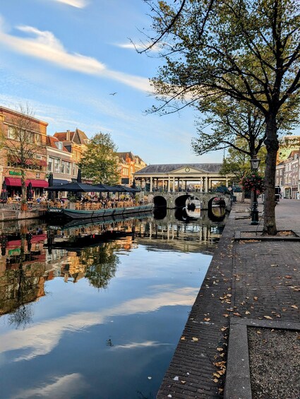 A canal with a bridge, a tree-lined walkway, and historic buildings. 1