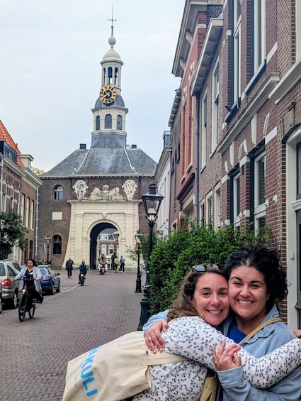 A historic building with a clock tower, a cobblestone street, and people walking. 4
