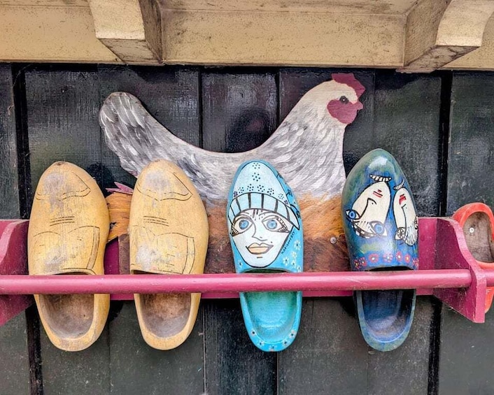 A row of colorful shoes with faces on the soles, arranged on a shelf against a wooden background. 3