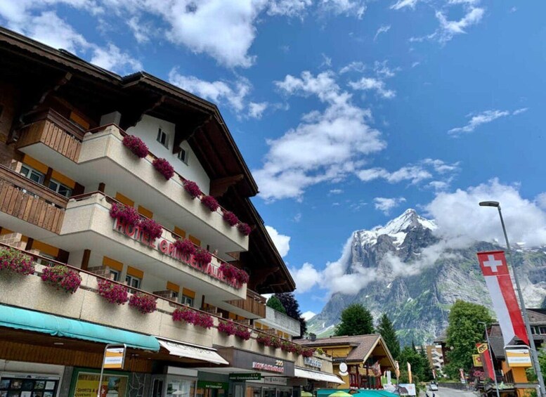 A hotel with balconies adorned with flowers, a mountain backdrop, and a Swiss flag. 5