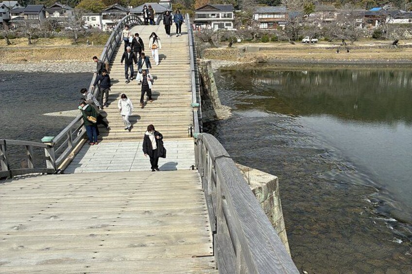 A wooden bridge over a body of water with people walking on it. 2