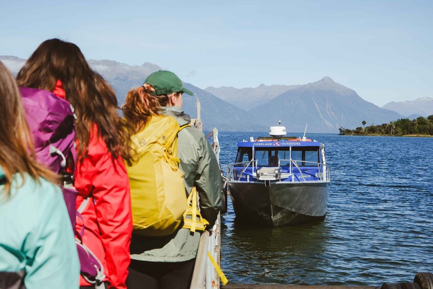 A group of people on a boat, a large body of water, and mountains in the background. 3