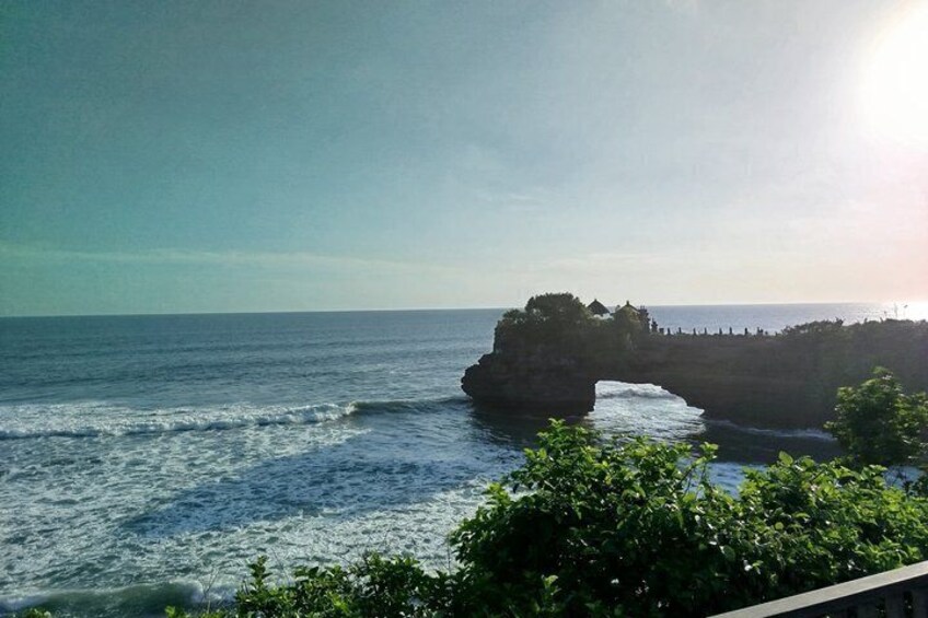 A coastal landscape with a prominent rock formation and a clear sky. 1