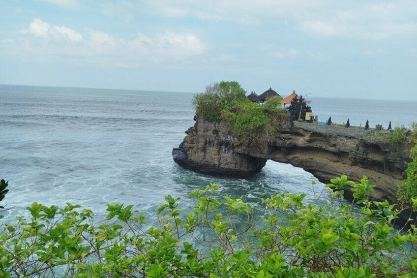 A coastal cliff with a small building and a thatched-roof structure. 3
