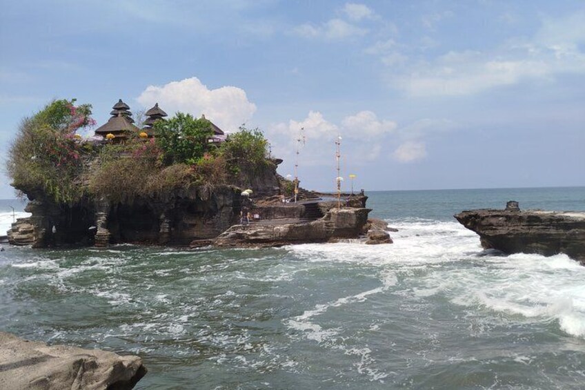 A rocky coastal area with traditional structures on top, surrounded by ocean waves. 2
