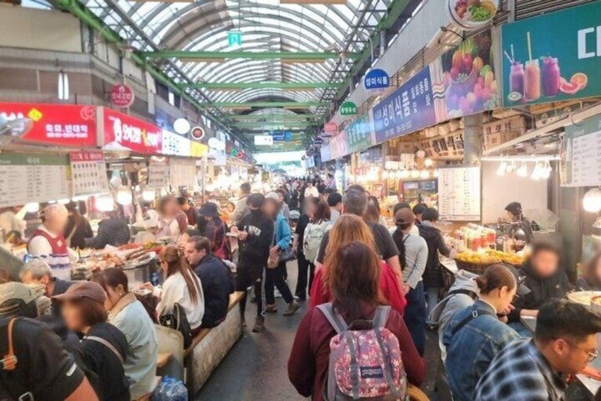 A crowded indoor market with people browsing and shopping. 3