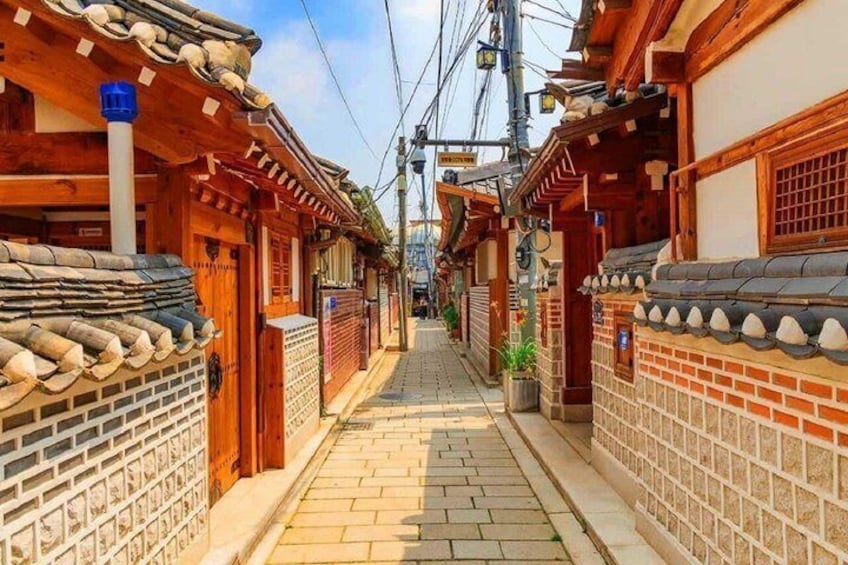 A narrow alleyway with traditional Korean architecture, wooden doors, and tiled roofs. 1