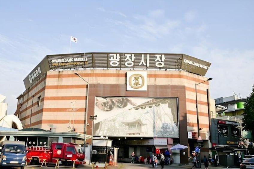 A building with a large mural and signage in a foreign language, surrounded by vehicles and people. 4